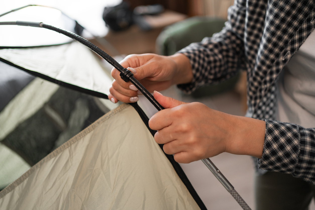 a woman preparing for mountain hike, assembling and checking tent frame at home
